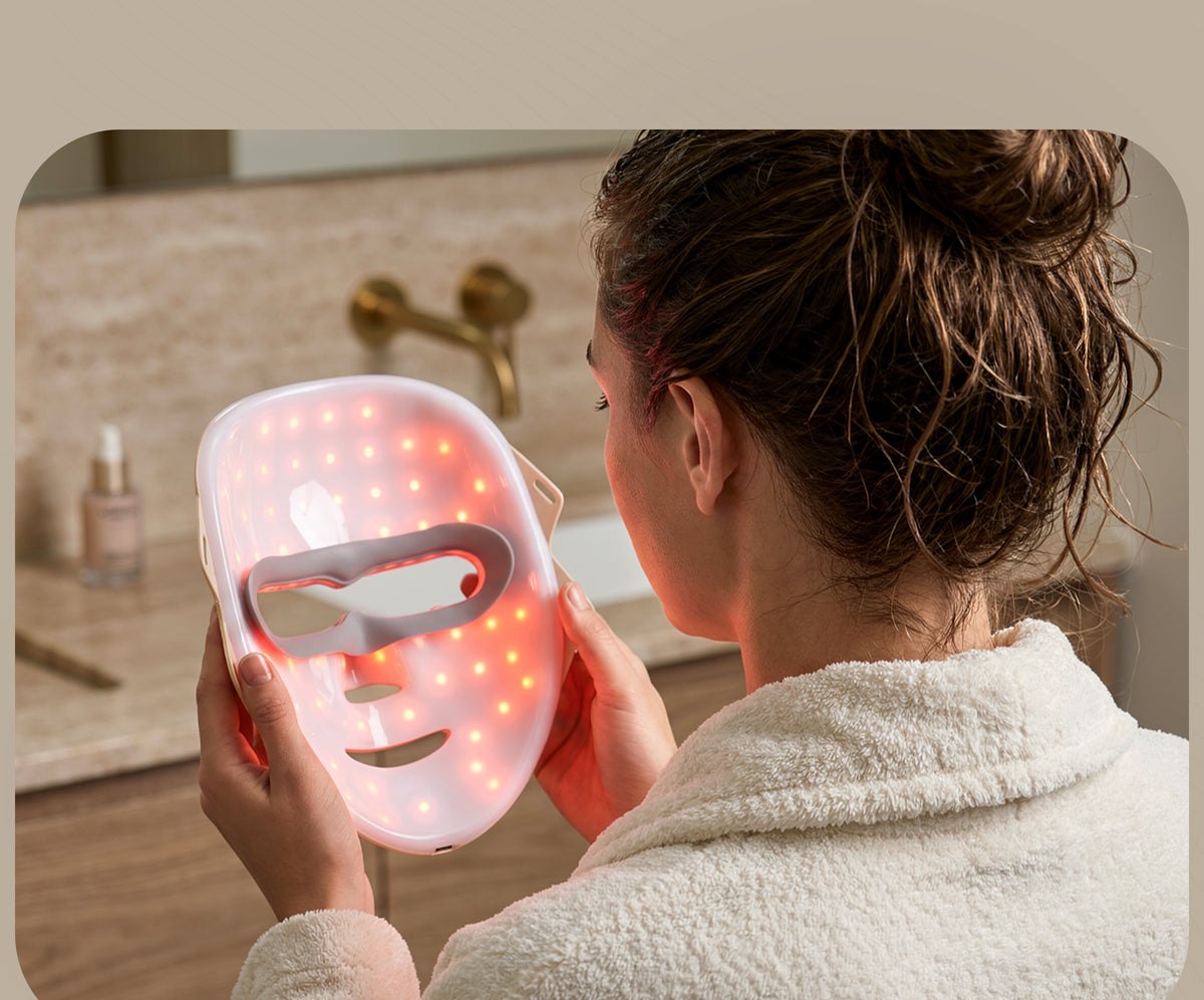 Woman holding the LED mask in her bathroom