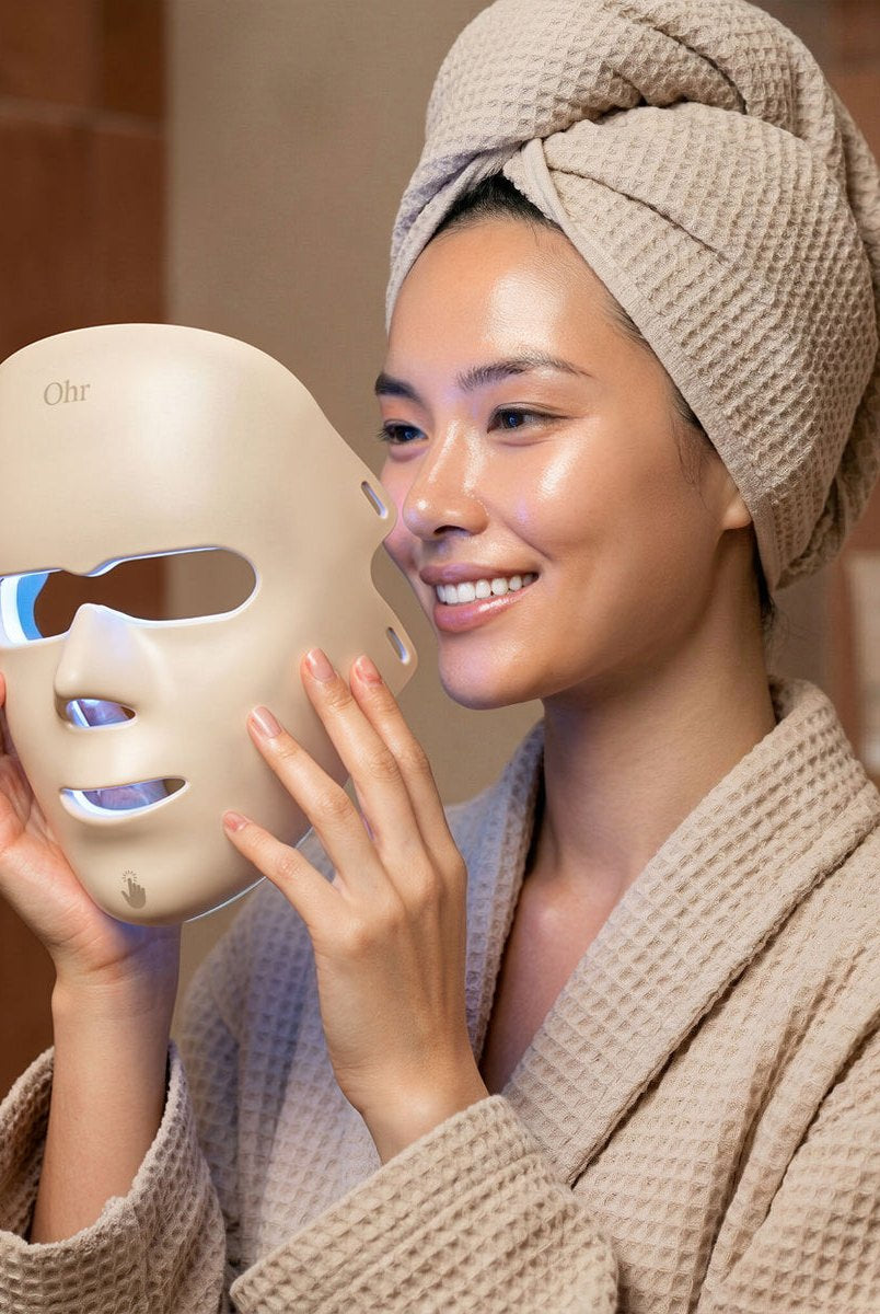 Woman in a bathrobe with the LED face mask